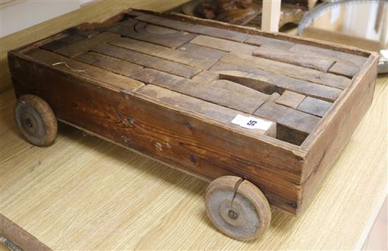 An Edwardian pine trolley housing a set of 20th century oak building blocks, 22.5in.